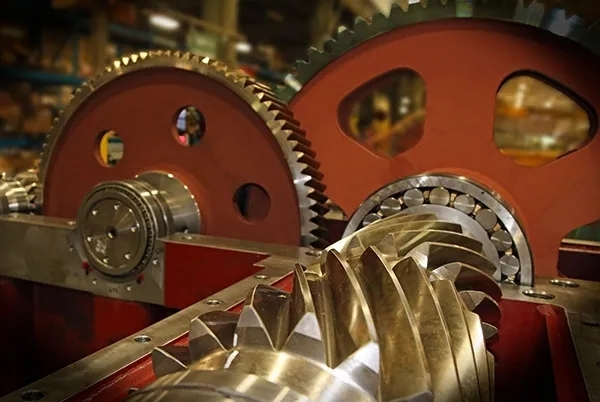 How do different types of gear arrangements affect load distribution in a gearbox system?